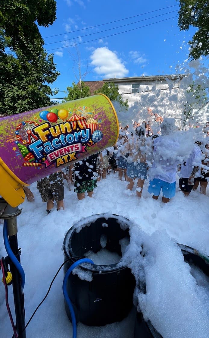 Fun Factory foam cannon spraying white foam over people at an outdoor summer party.